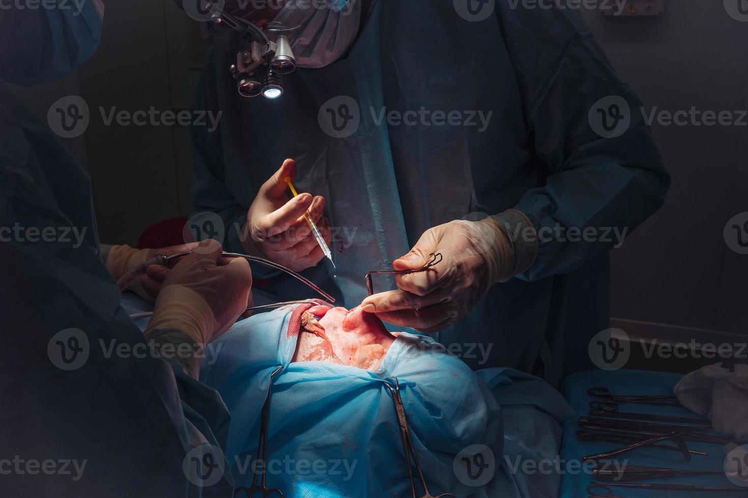 Surgeon and his assistant performing cosmetic surgery on nose photo