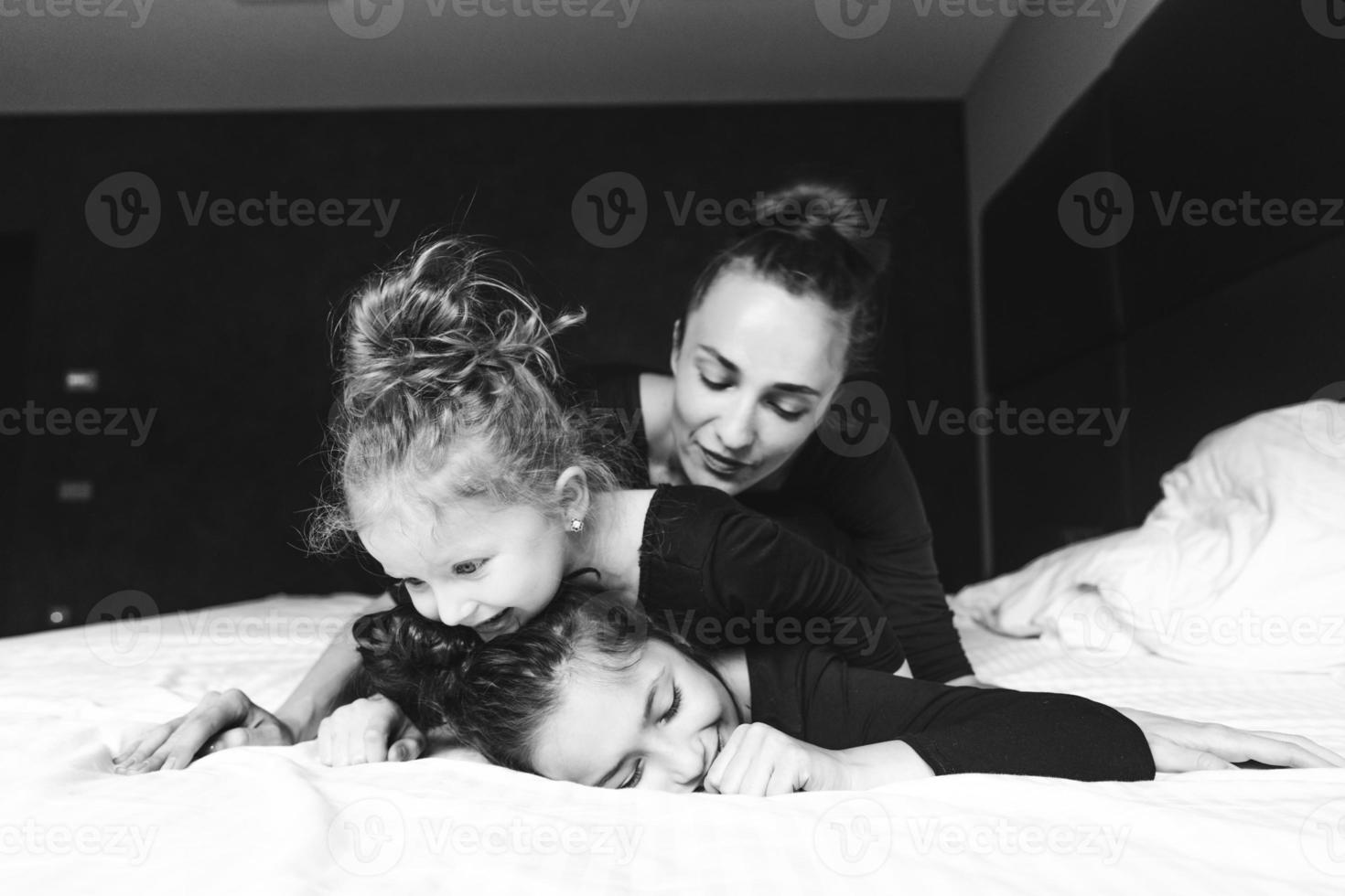 Mom and two daughters have fun on the bed photo