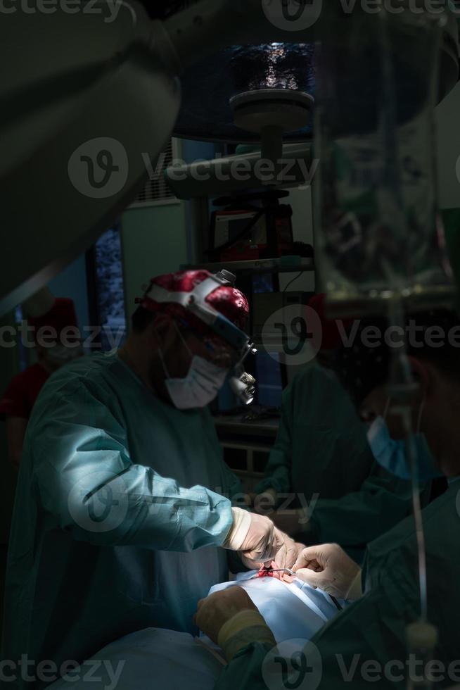 Surgeon and his assistant performing cosmetic surgery on nose photo