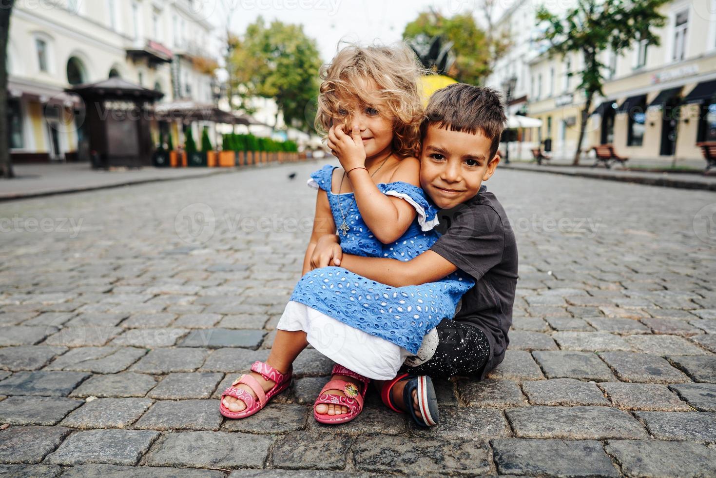 little boy and girl are sitting on the street photo