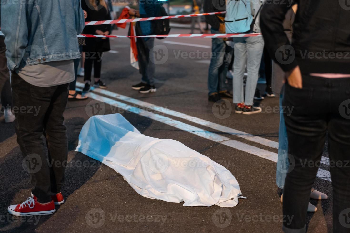 Human body covered by a sheet lying on the street. photo