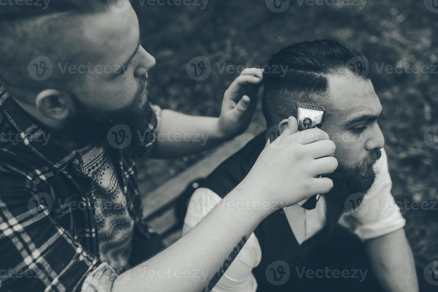 barbero afeita a un hombre barbudo foto