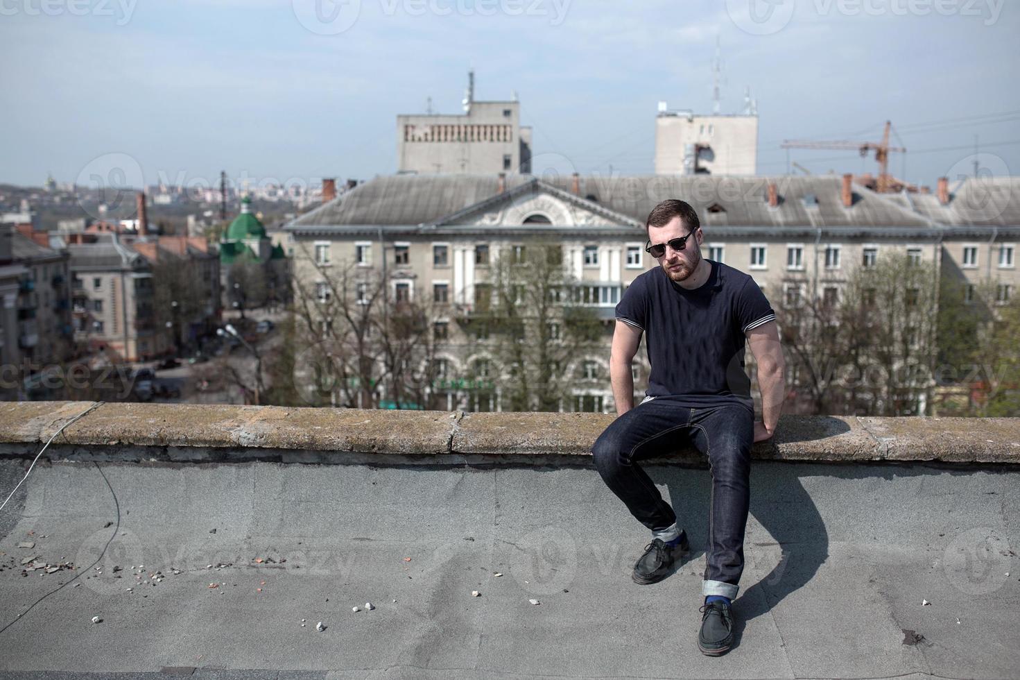 El hombre de las botas auténticas y el orillo de jeans en el techo del edificio en el casco antiguo foto