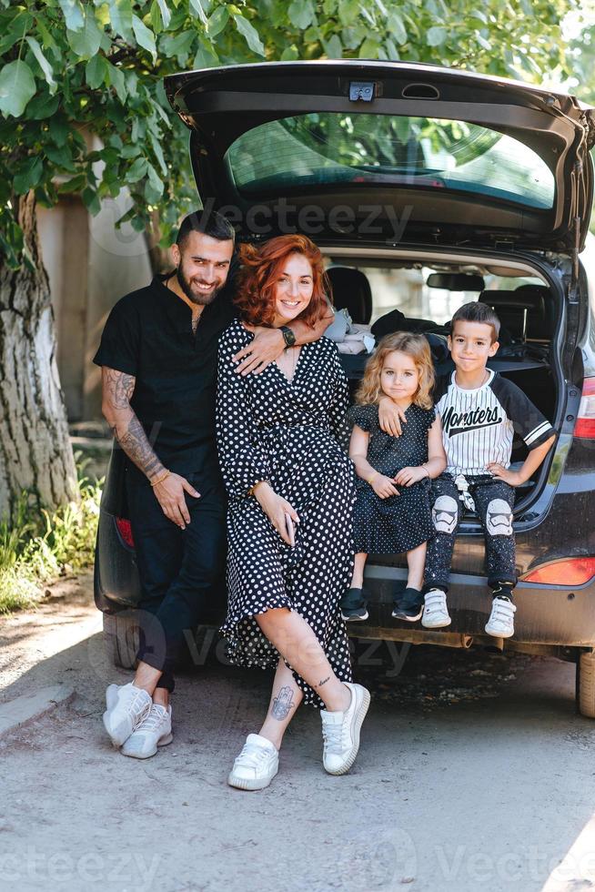 Happy family posing on camera near the car photo