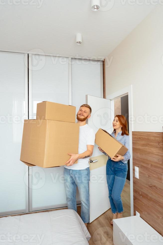 Happy couple holding cardboard boxes and moving to new place photo