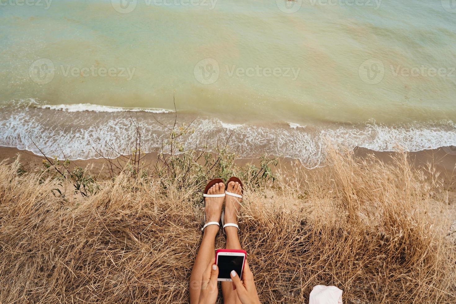 beautiful young girl sitting and holding a smartphone in her hands, top view photo