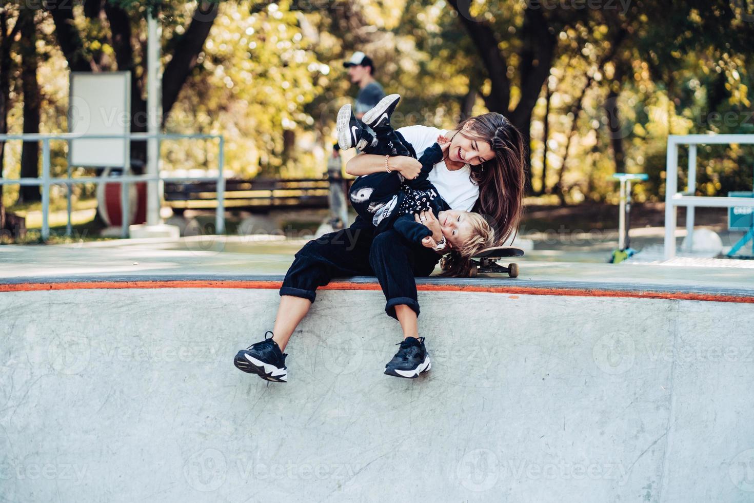 Beautiful young hipster mom and little son at the skatepark photo