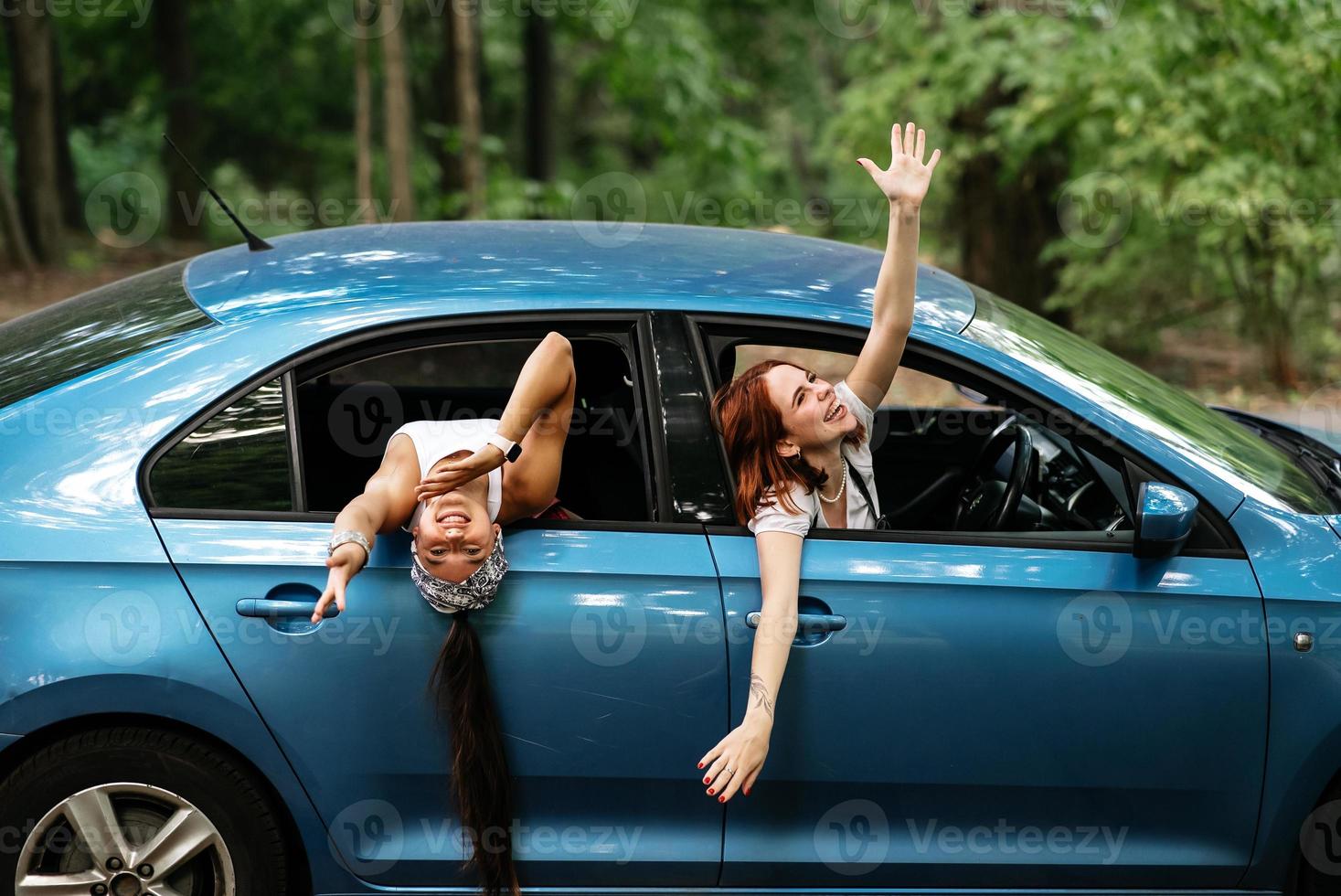 Two girlfriends fool around and laughing together in a car photo