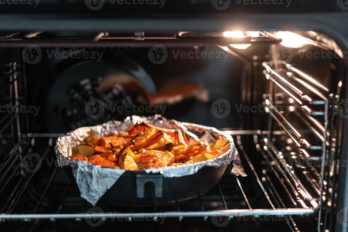 Baked potatoes with carrot and other spices in roasting pan. photo