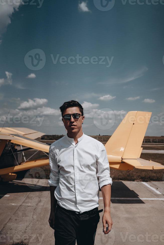 A man standing on the background of a small single engine plane. photo
