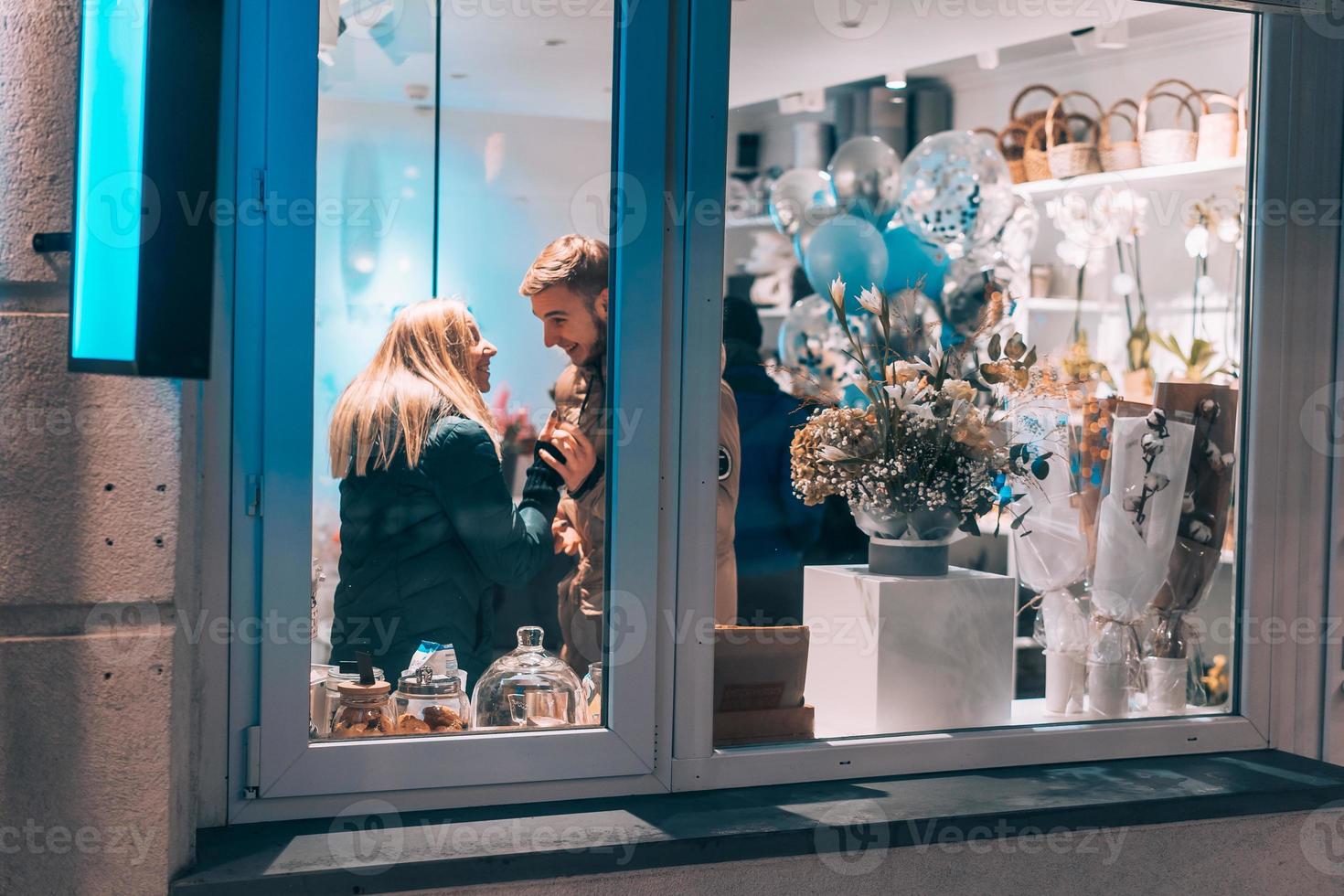 Photo through window. Young couple in cafe with stylish interior