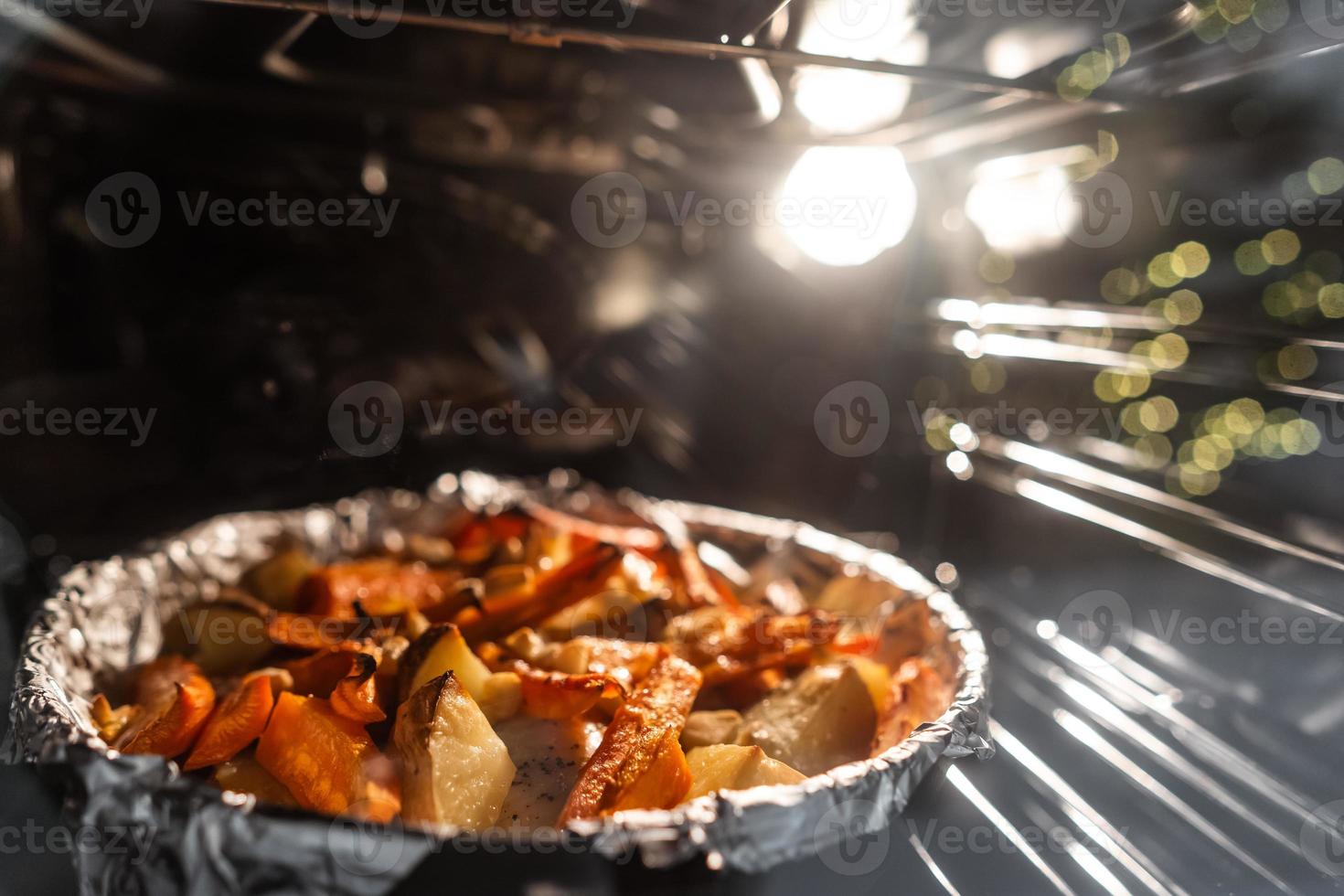 Baked potatoes with carrot and other spices in roasting pan. photo