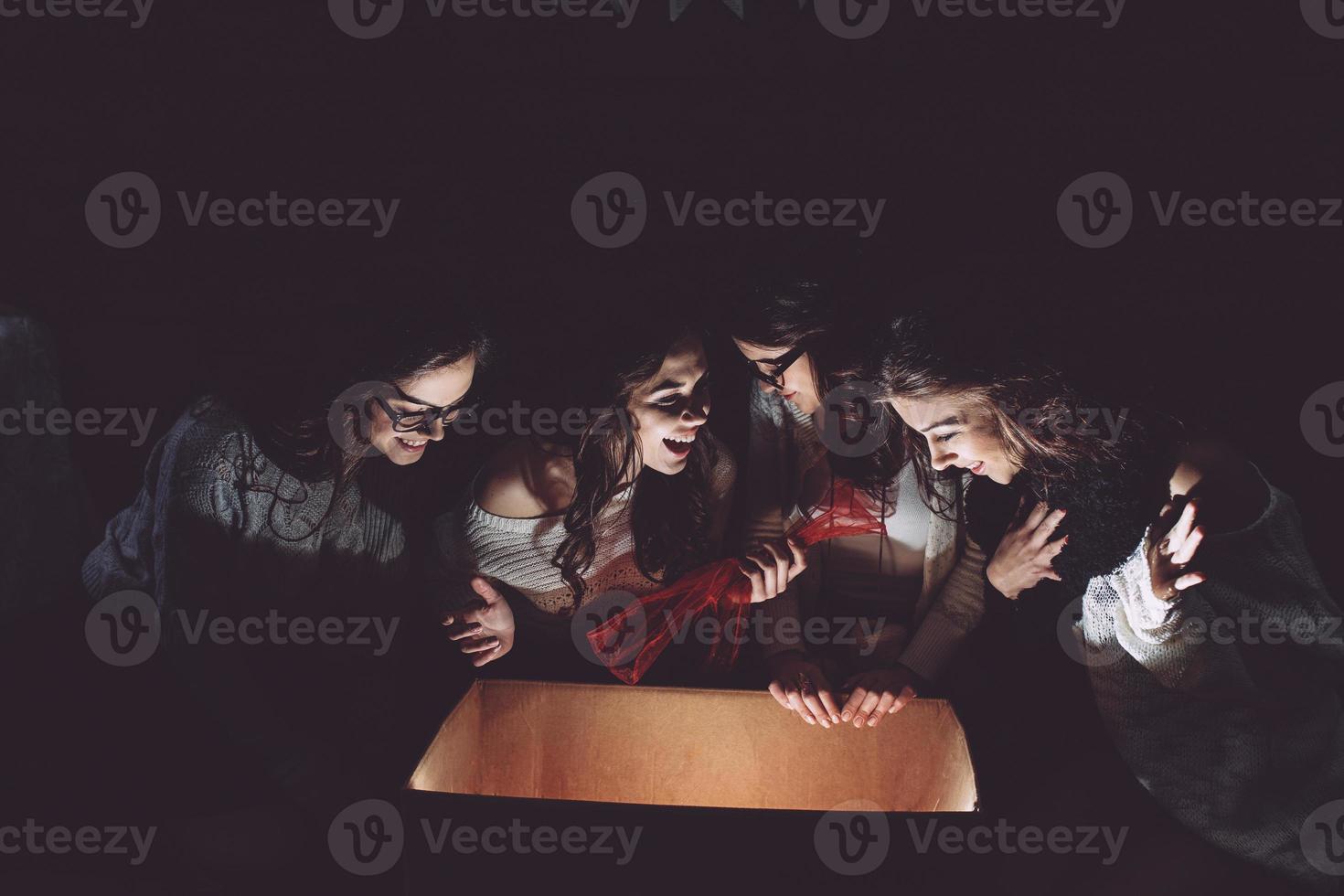 Sisters opens a box with a Christmas present and fascinated looks inside photo