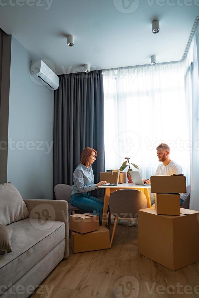 Young man and woman sitting at table, working at laptop in co-working office photo