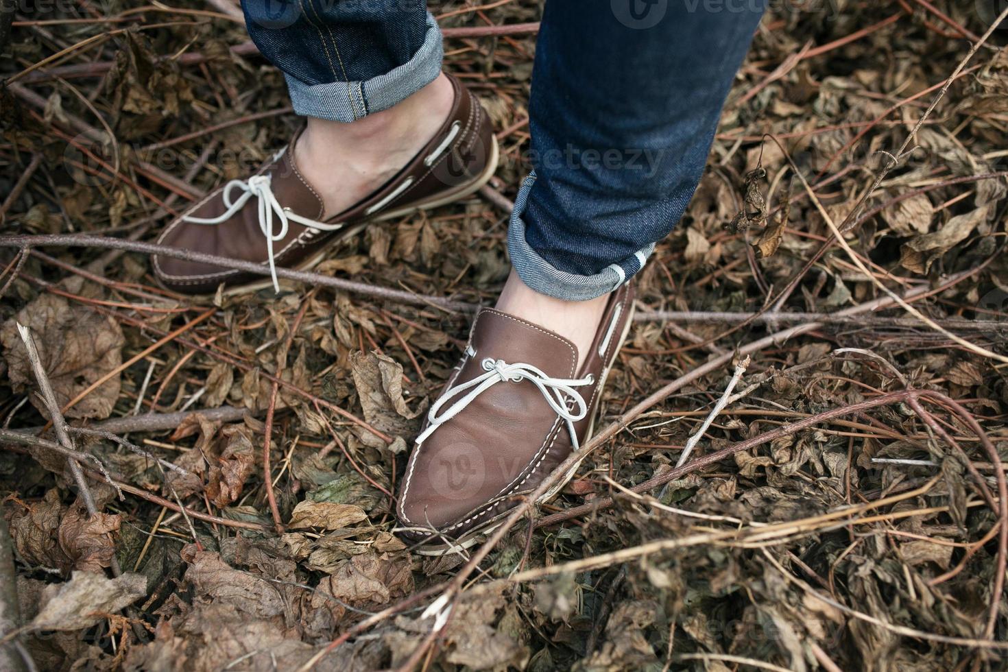 pies del hombre con botas auténticas y vaqueros de orillo, en el fondo de las ramas foto