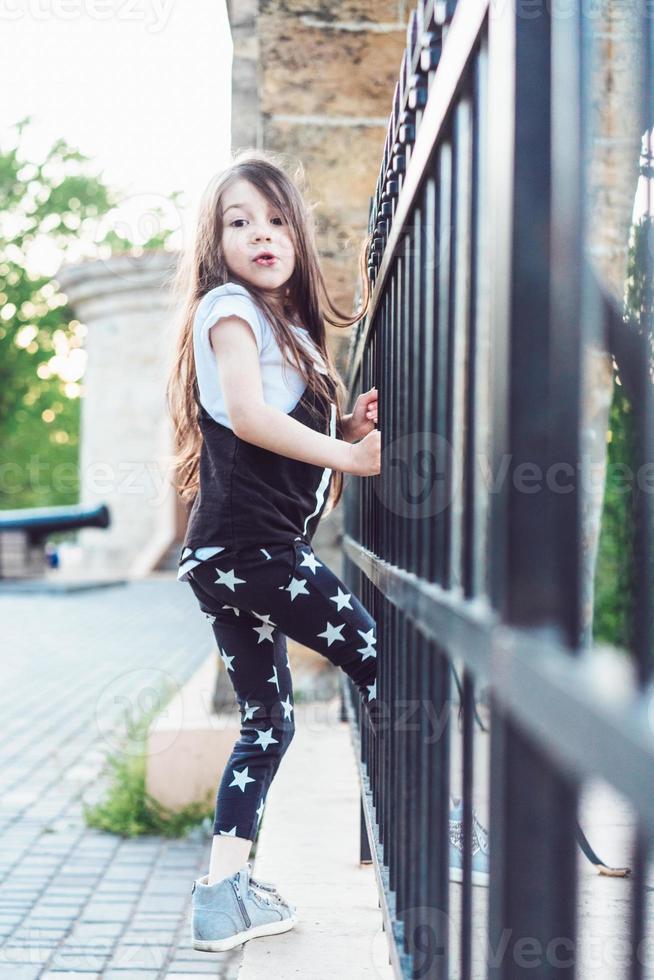 Little girl playing at fence photo