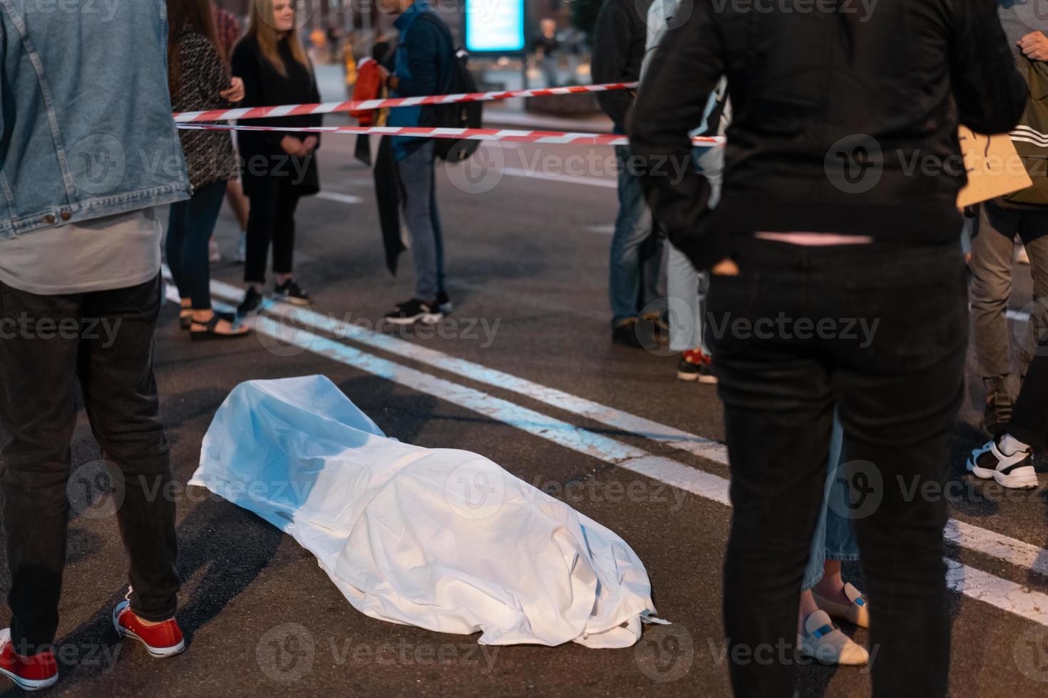 Human body covered by a sheet lying on the street. photo