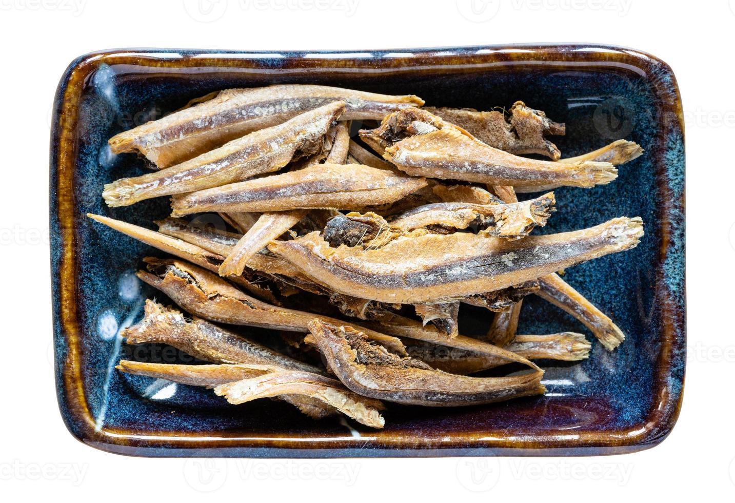 dried anchovy fishes in ceramic bowl isolated photo