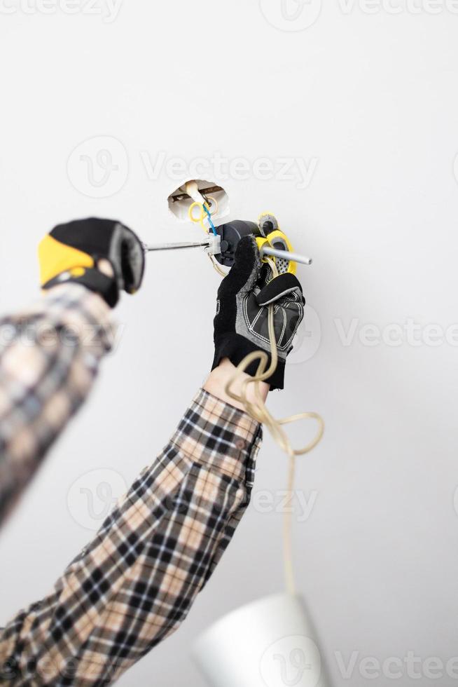 electrician fixes electrical wiring of lamp photo