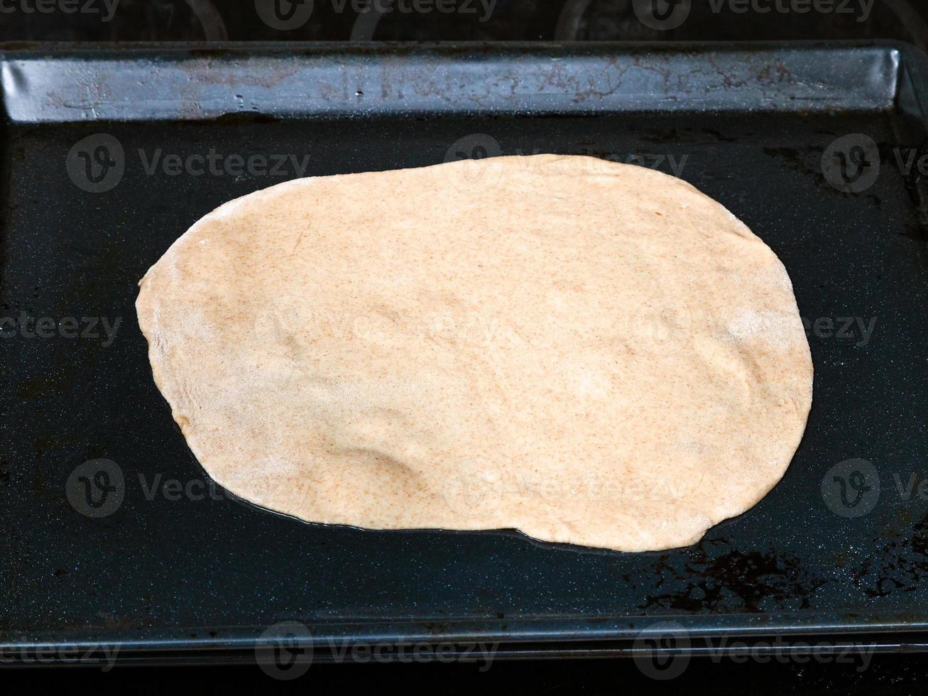 flat raw dough on baking tray photo