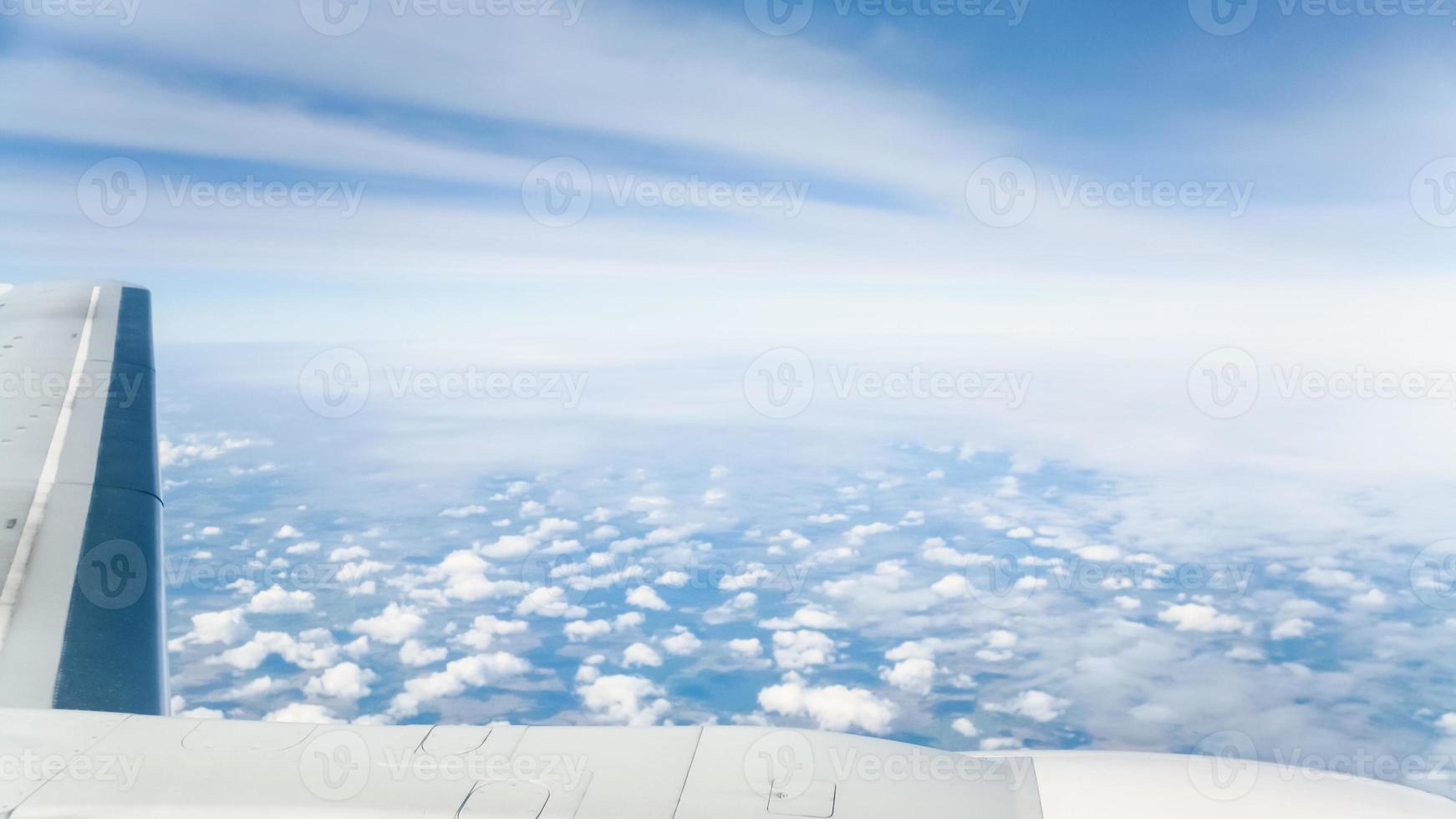 wing of aircraft and view of clouds over land photo