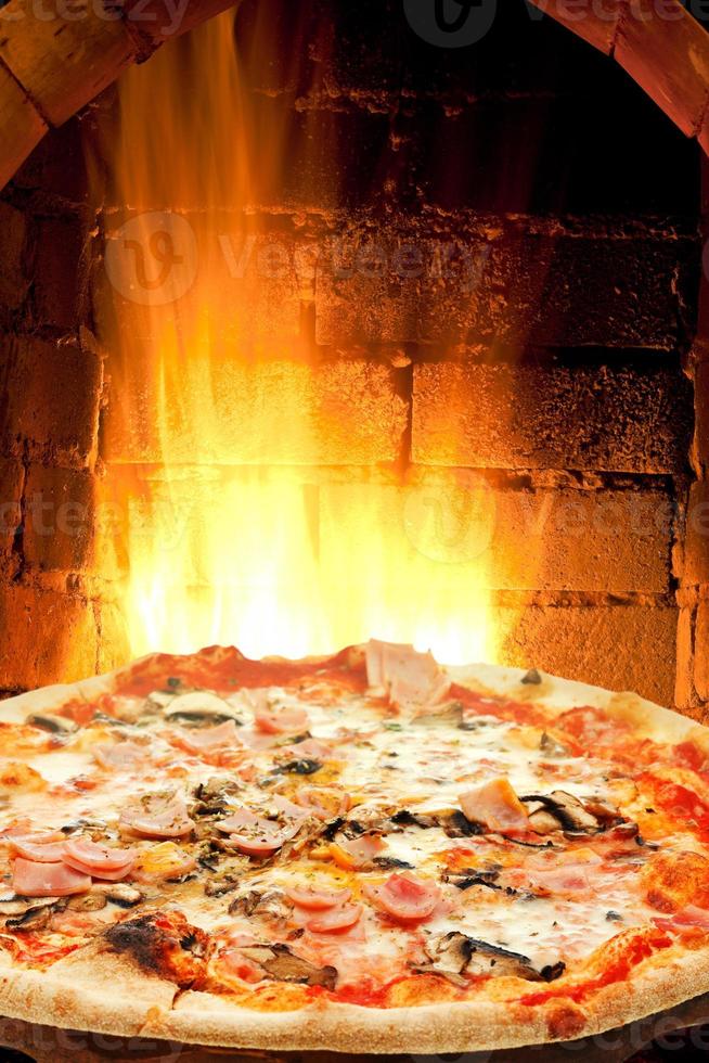 pizza with ham, mushroom and fire flames in oven photo