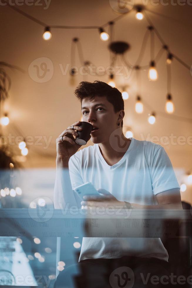 un hombre joven y guapo está bebiendo su café matutino en una cafetería. foto