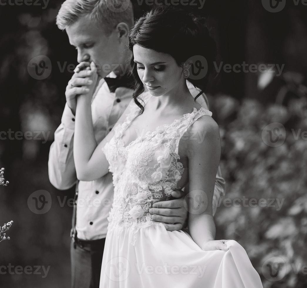 groom gently embracing his bride photo