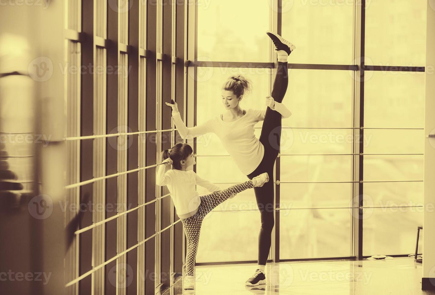 Mother learning daughter to make a high leg strech photo