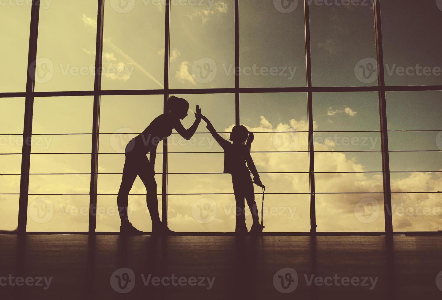 Silhouette of mother and daughter in the gym.high five. photo