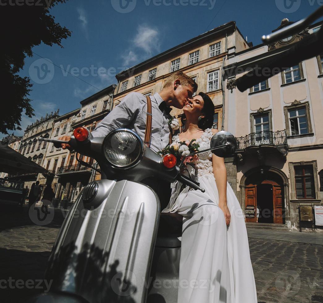 bride and groom on vintage motor scooter photo