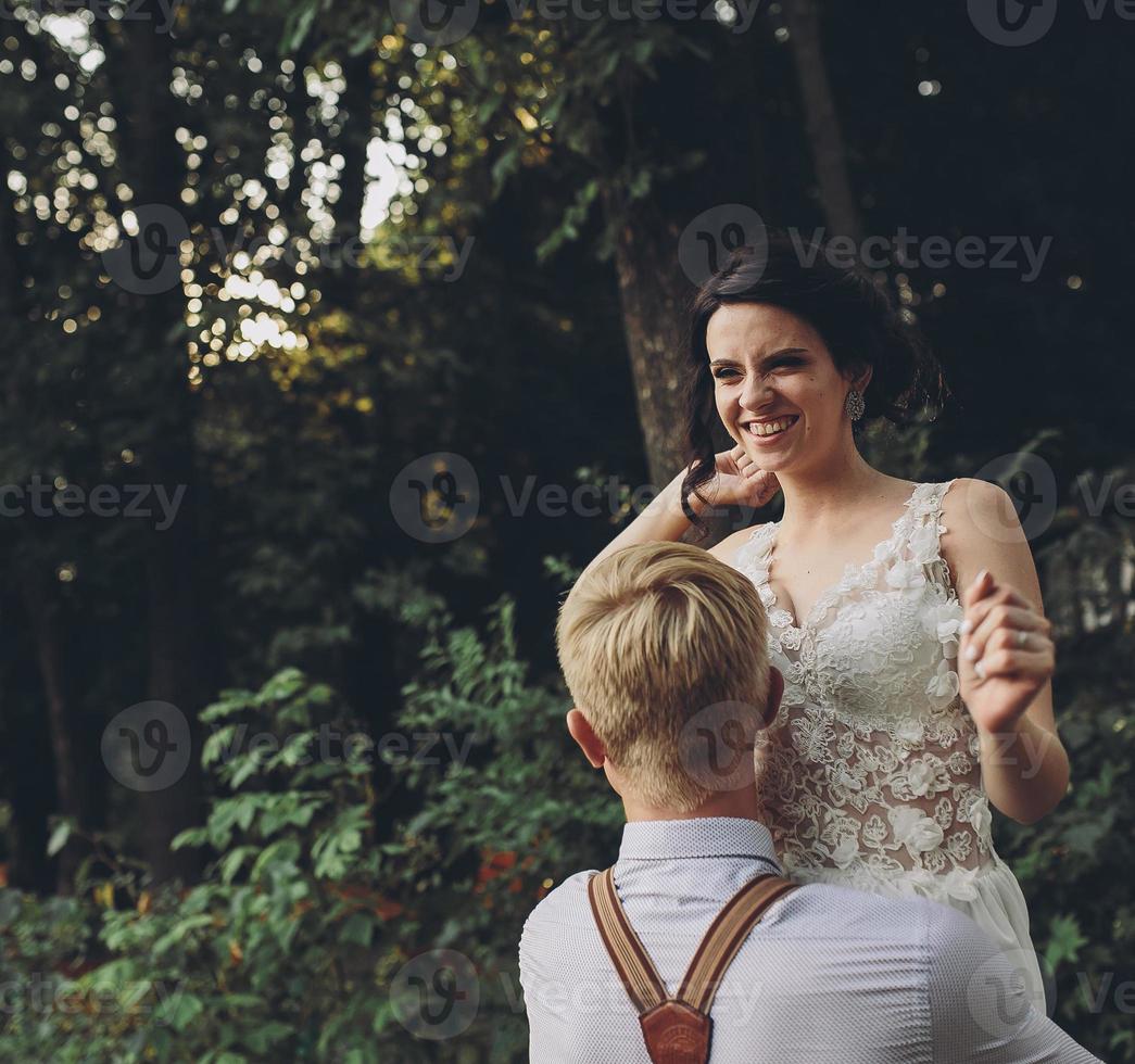 groom holds bride in his arms photo