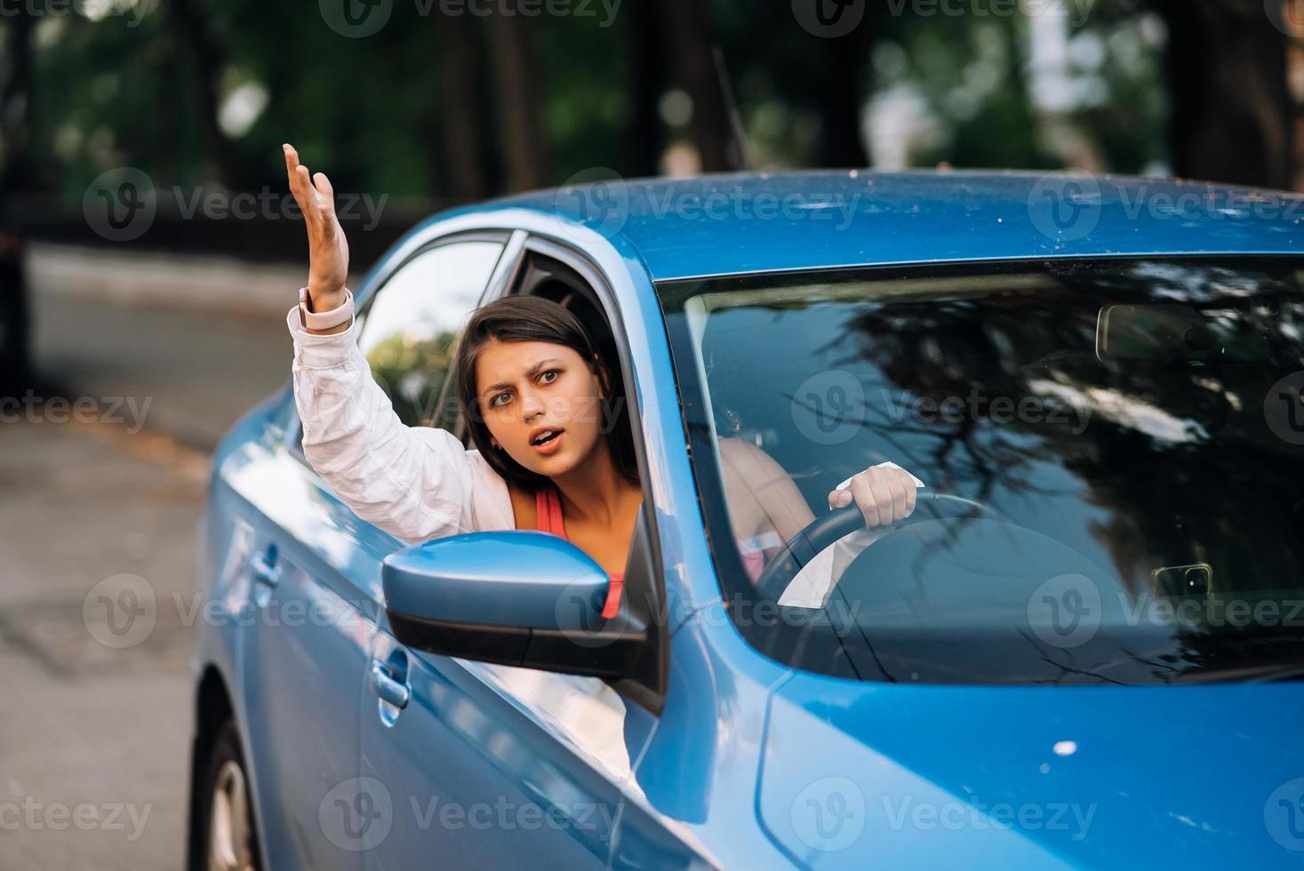 A young angry woman peeks out of the car window photo