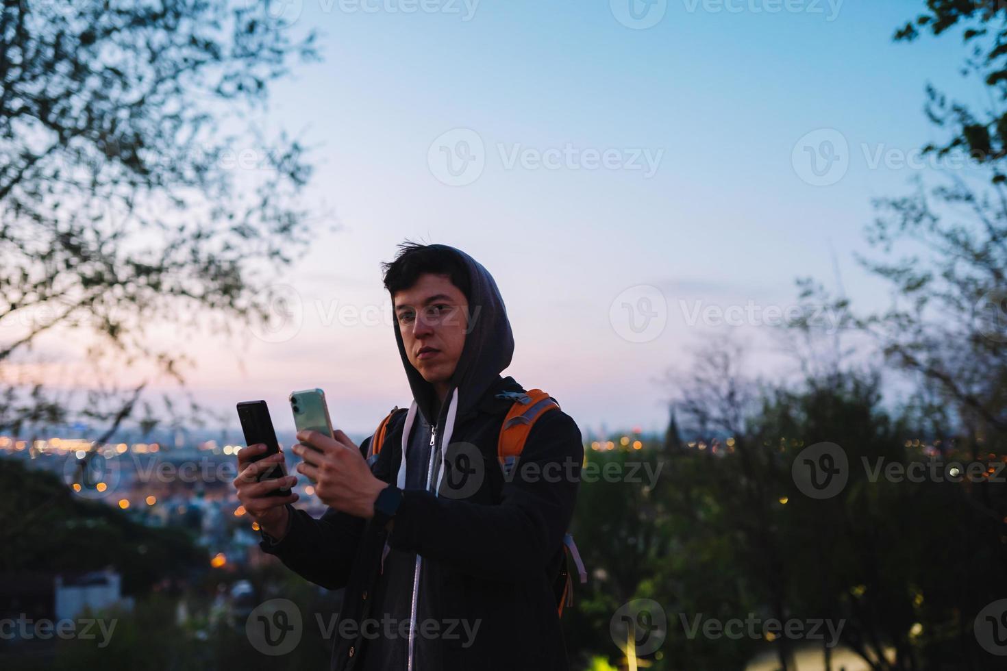 joven en el parque toma una foto en dos teléfonos inteligentes