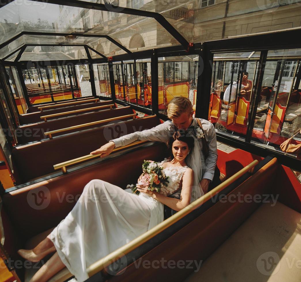 Bride and groom posing in a tour car photo