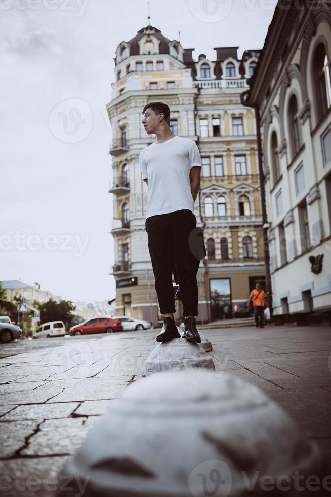 Guy stand on the city street, look camera and around photo