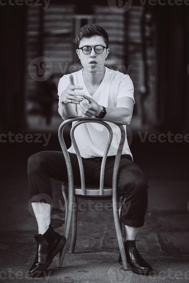 portrait of men sitting on chair with white t-shirt and sunglasses in the street photo