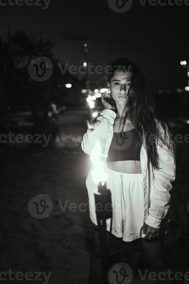 mujer joven con antorchas en la playa por la noche foto