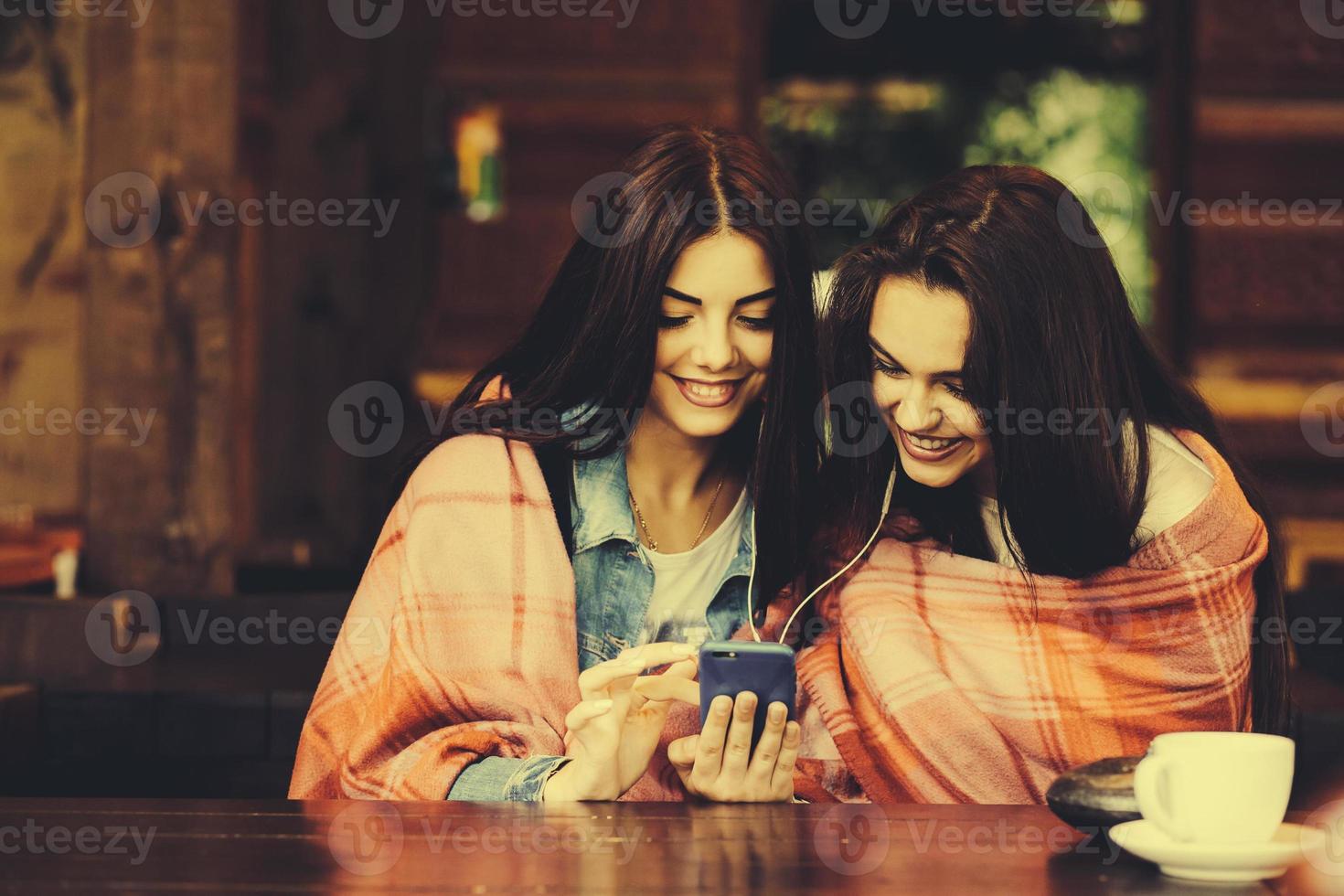 dos chicas sentadas escuchando música con un smartphone foto