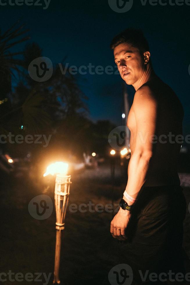 Guy with torchlight on the beach at night photo