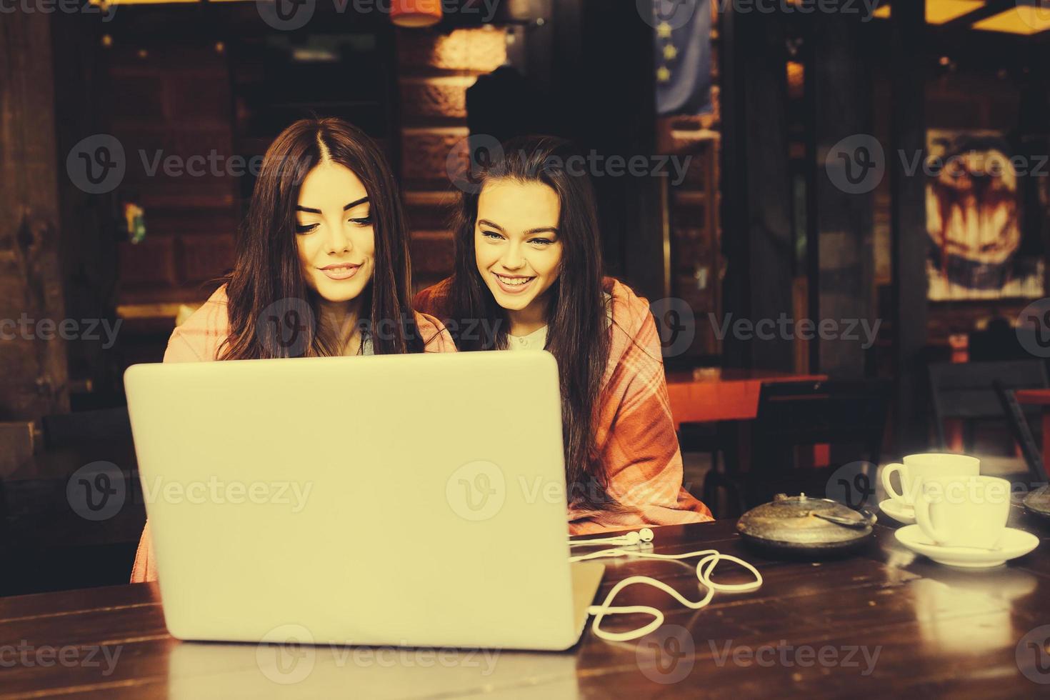 two girls watching something in laptop photo