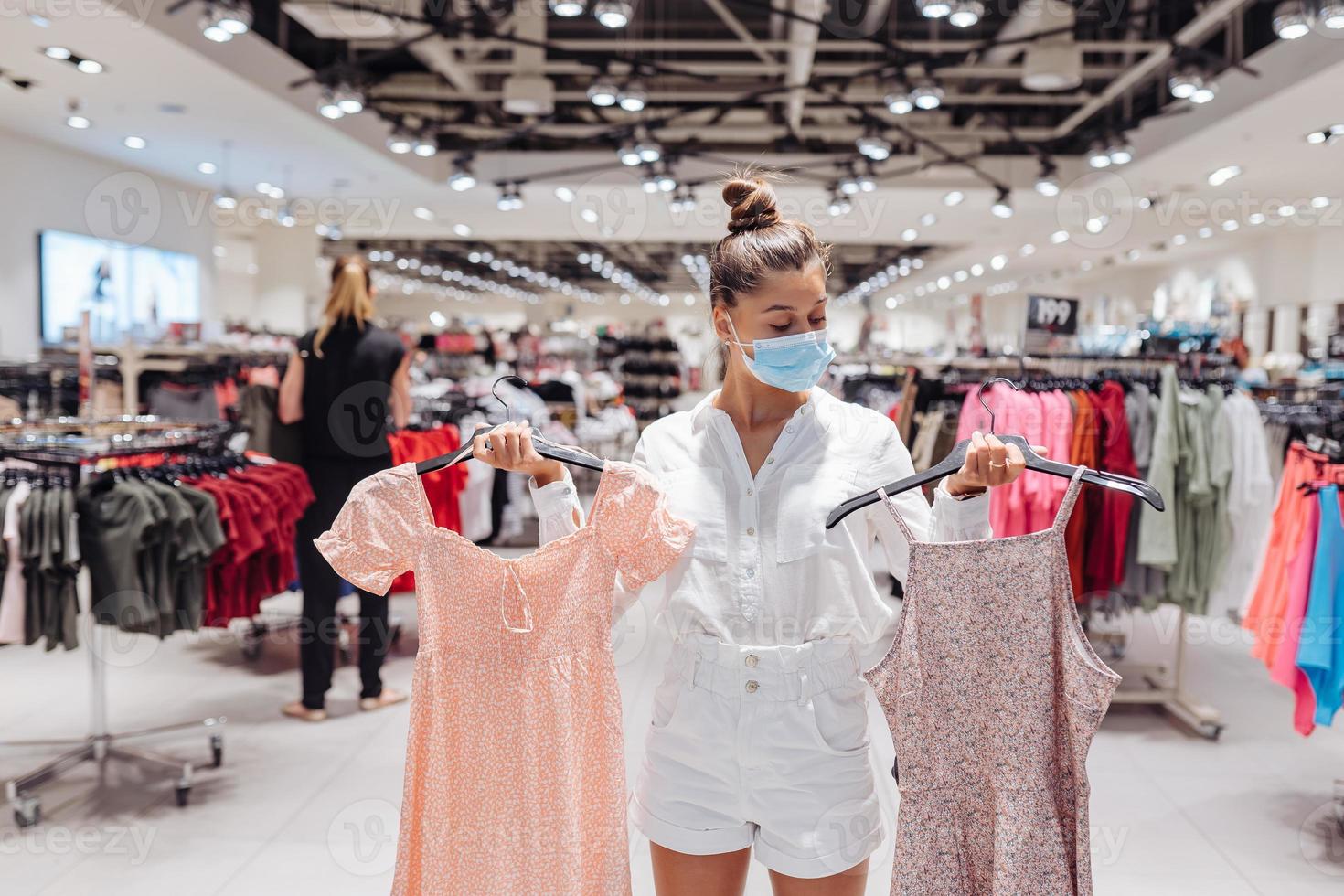 mujer joven comprando ropa en una boutique de ropa con mascarilla protectora foto