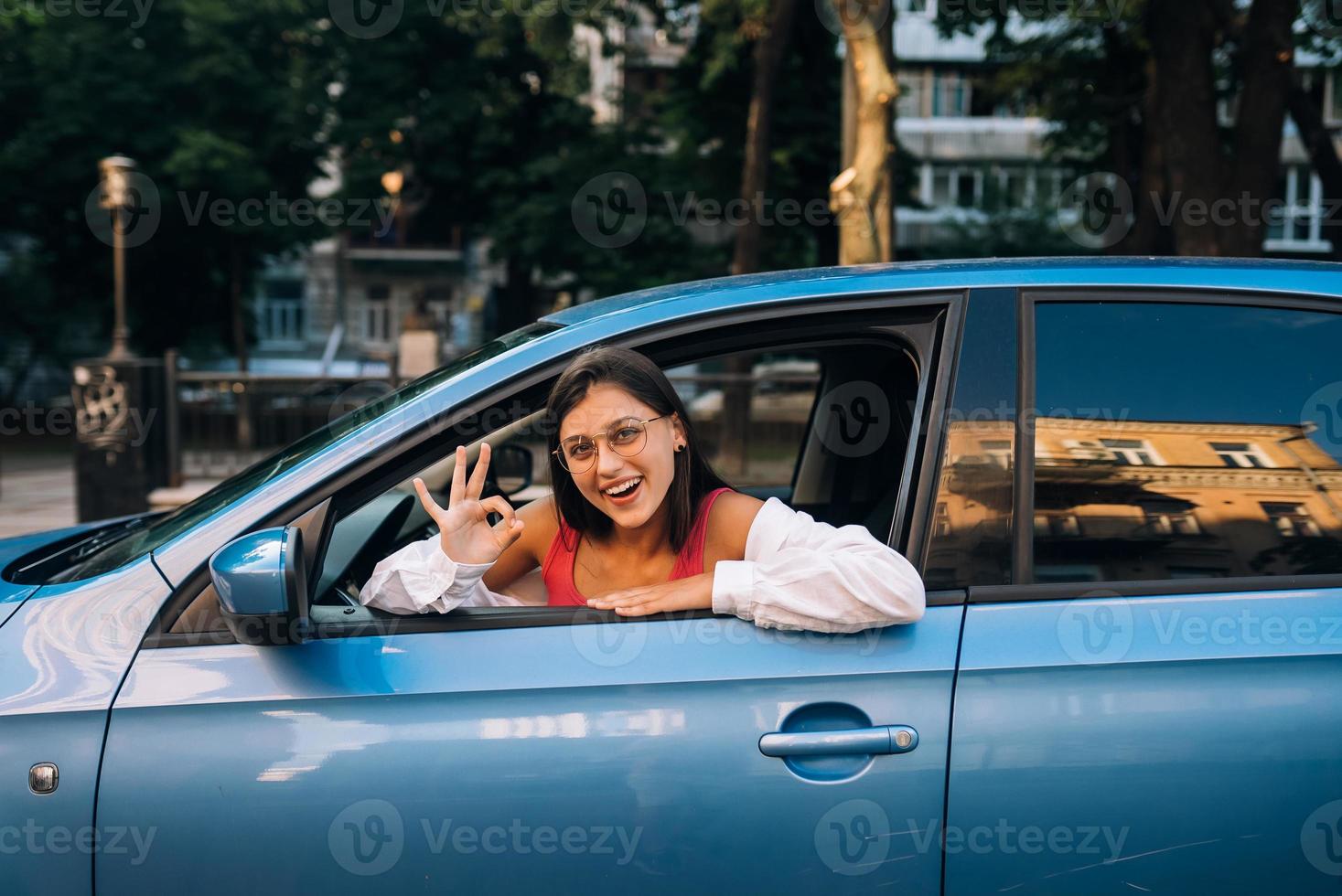 Happy woman in a car, looking out of the window. photo