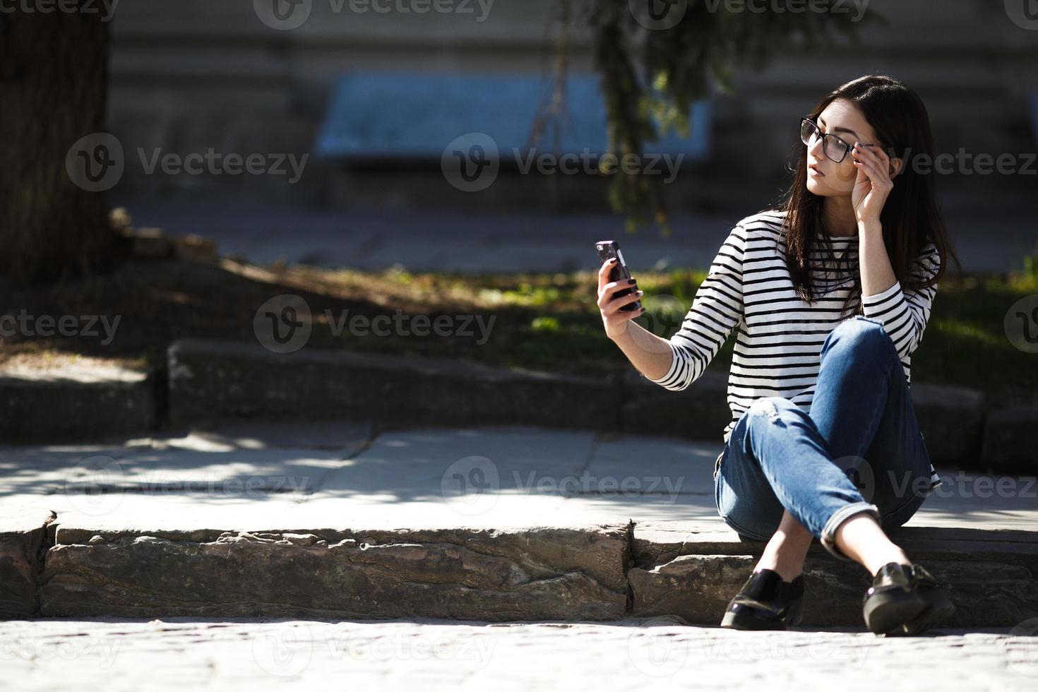 model in the middle of the city with phone photo
