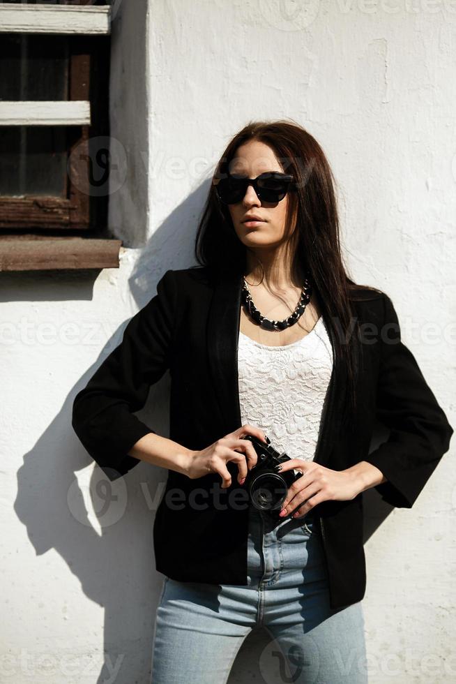 hermosa chica de pie contra una pared con una cámara foto
