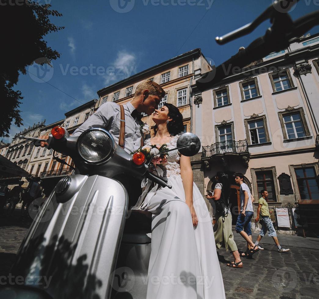 bride and groom on vintage motor scooter photo