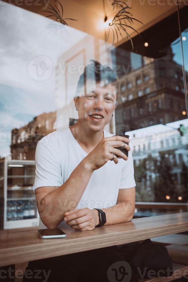 un hombre joven y guapo está bebiendo su café matutino en una cafetería. foto