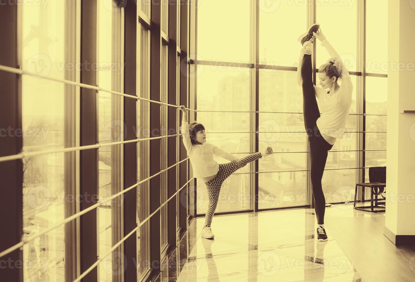 Mother learning daughter to make a high leg strech photo