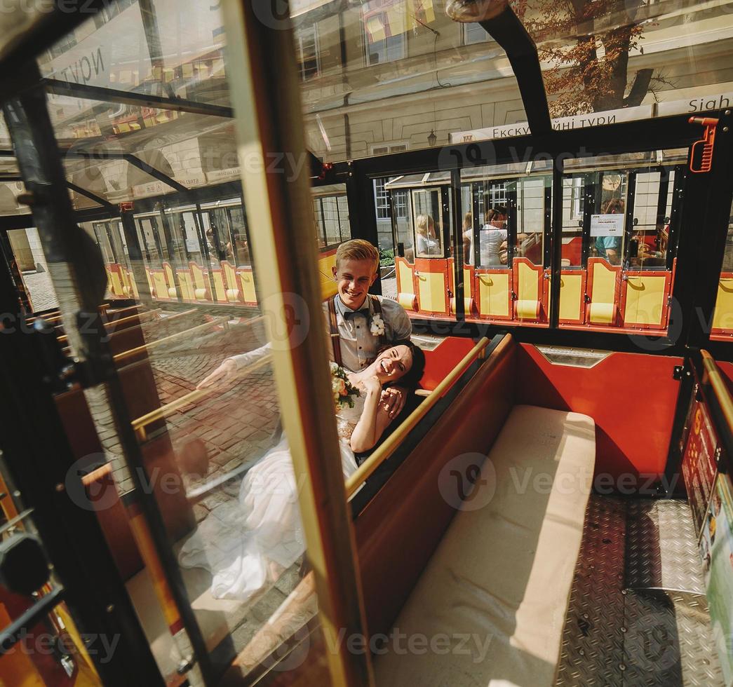 Bride and groom posing in a tour car photo