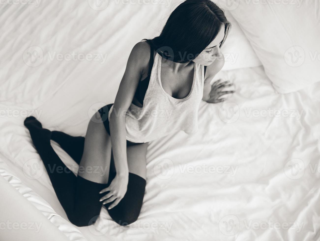 beautiful young girl posing on a white bed photo